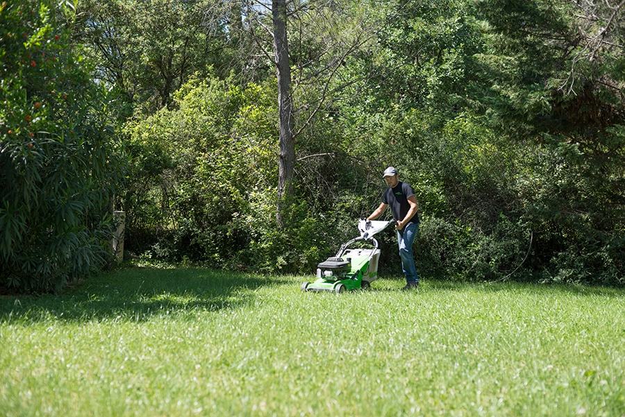 Technicien de Marcadier Paysage passant la tondeuse dans un jardin méditerranéen